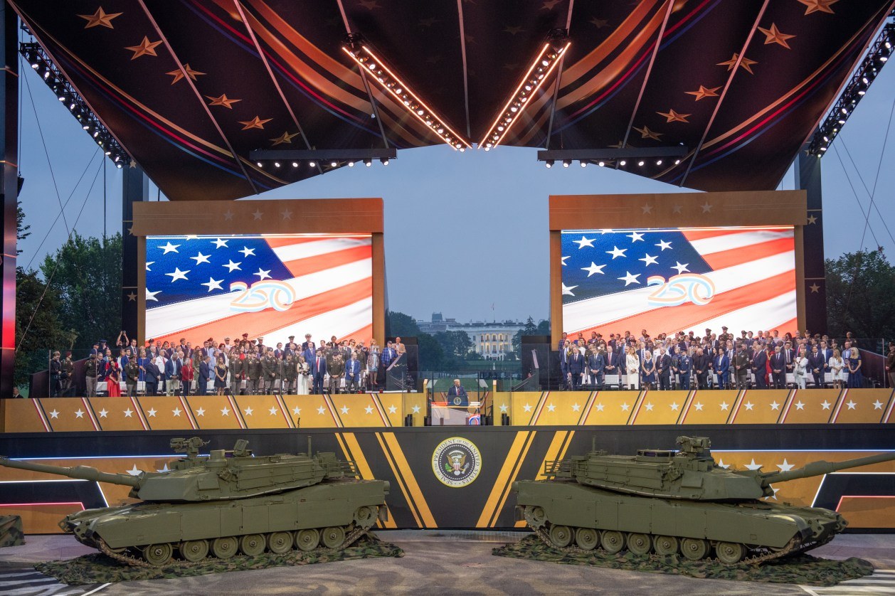 Patriotic outdoor stage celebration with American flags and military tanks